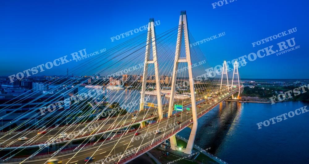 Фотография изображает Большой Обуховский мост, также известный как Вантовый мост, в вечернее время суток. Этот снимок идеален для использования в проектах, связанных с градостроительством, архитектурой и городским дизайном, а также может привлекать внимание фотографов и любителей городского пейзажа.